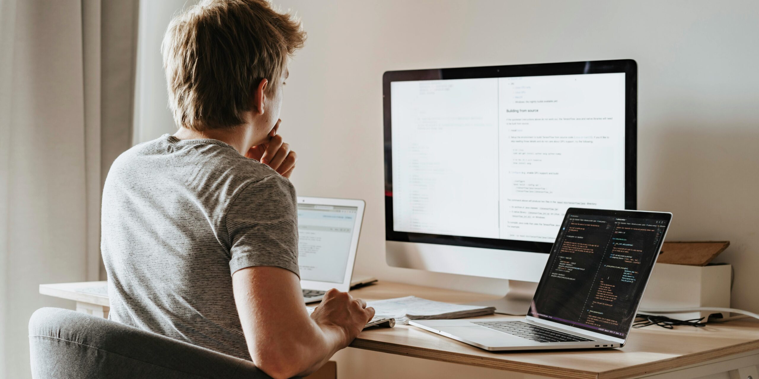Thinking at the Computer A man sits with multiple computers around him, possibly working.
