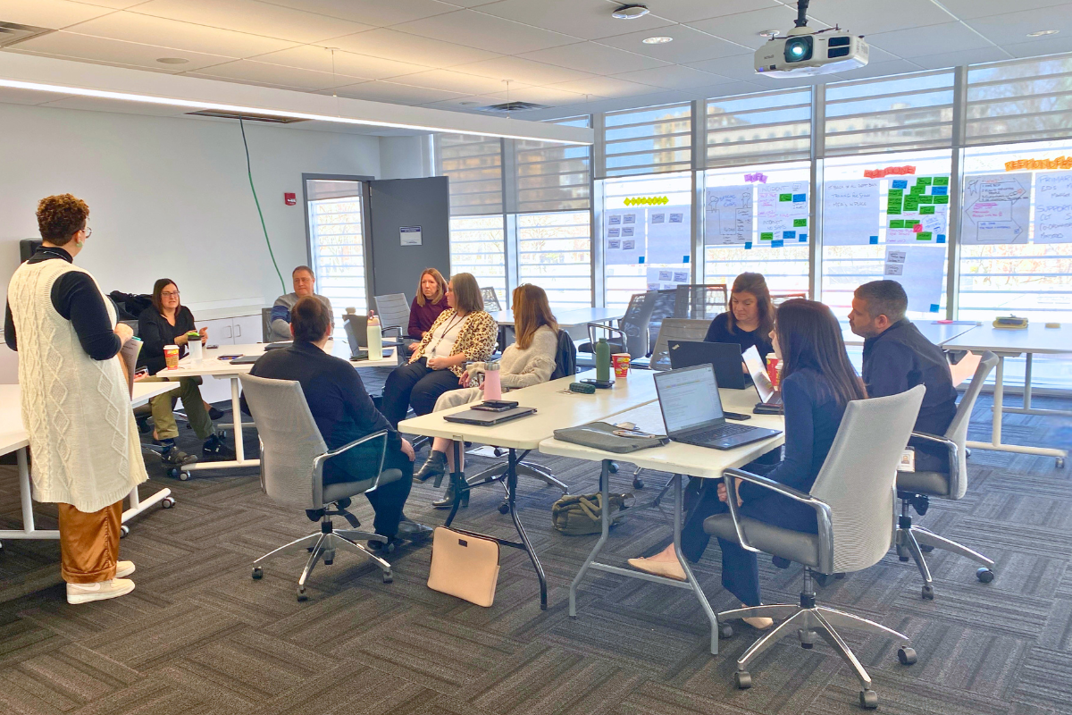 A room full of people at tables having a meeting
