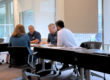 a small team sits at a table having a meeting in an office