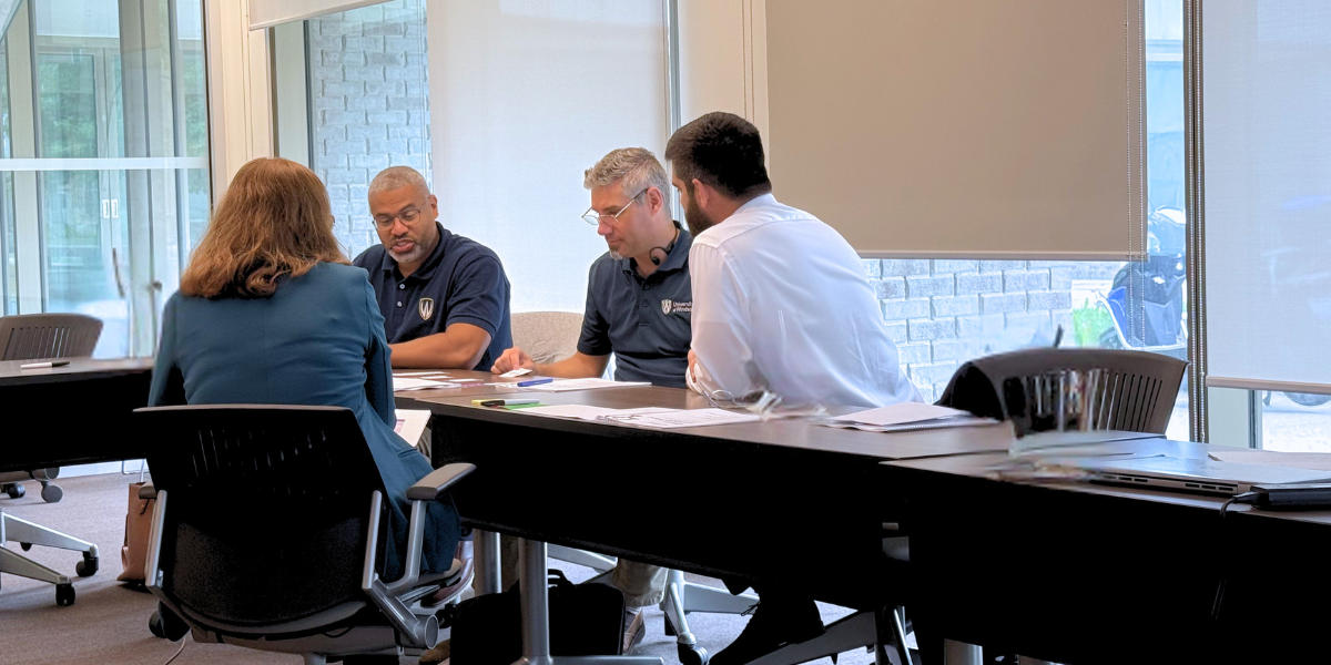 a small team sits at a table having a meeting in an office