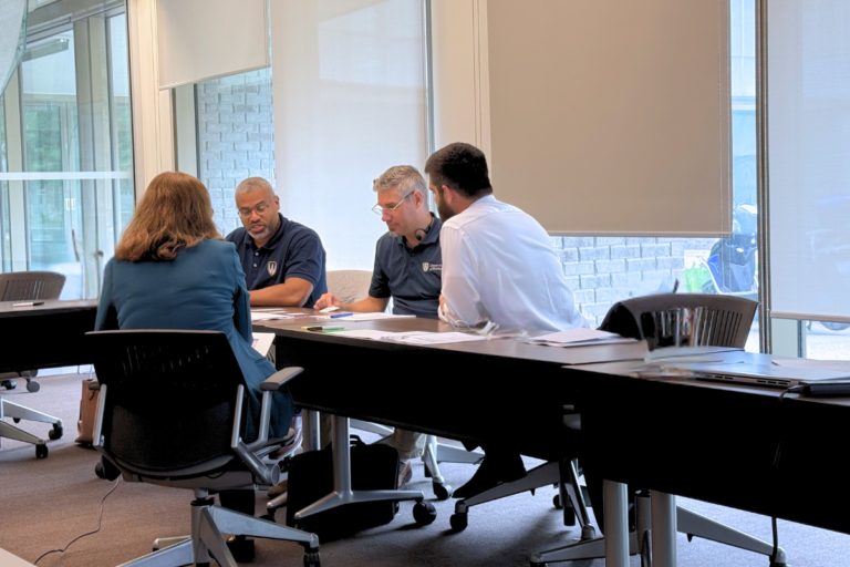 a small team sits at a table having a meeting in an office