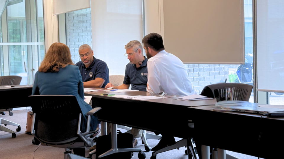 a small team sits at a table having a meeting in an office