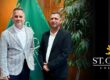 two men in front of flag in board room